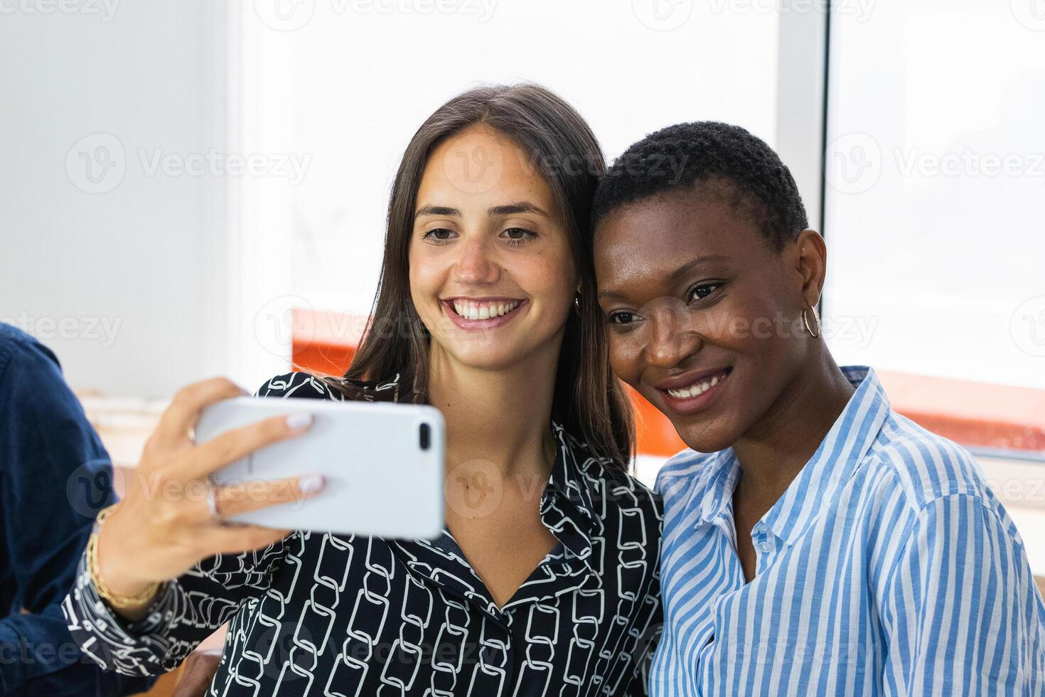 Smiling multiethnic coworkers taking selfie during break in office photo