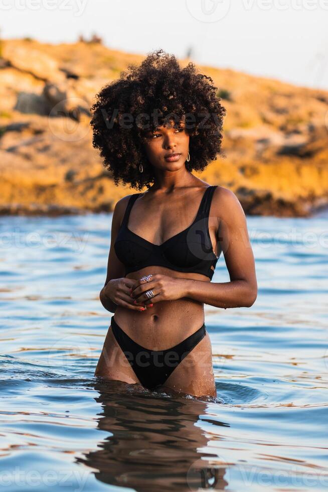 Calm ethnic woman in bikini in sea photo