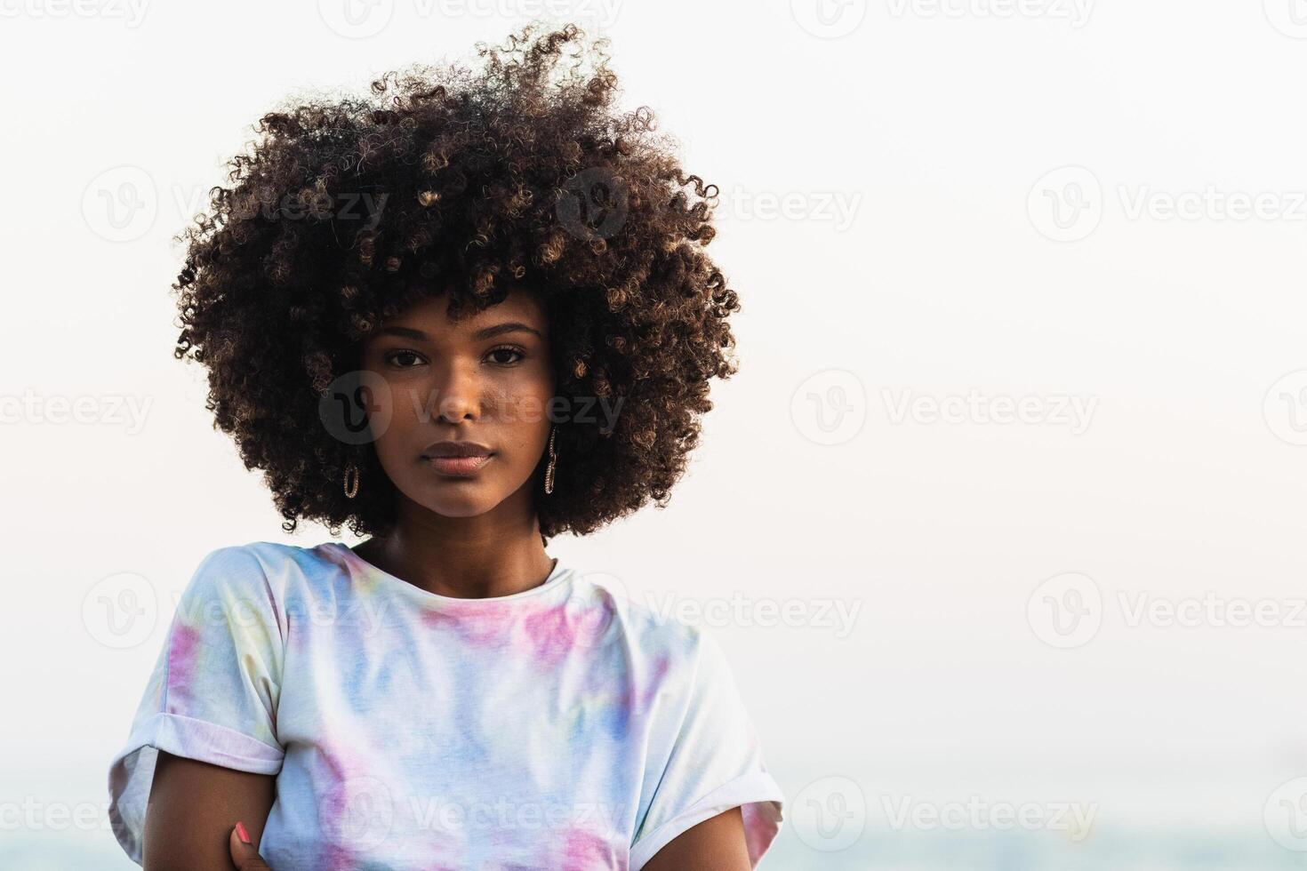 Unemotional black woman standing on seashore photo