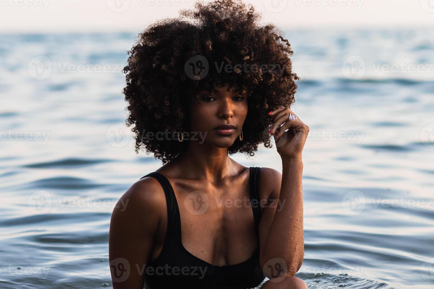 Calm ethnic woman in bikini in sea photo