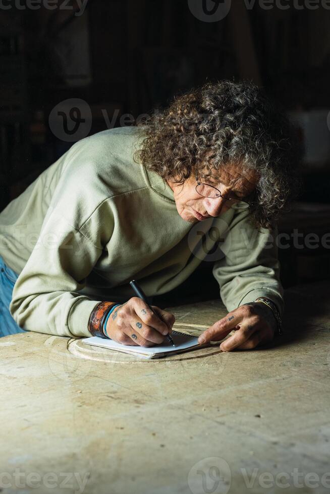 Male carpenter creating sketch in notebook in workshop photo