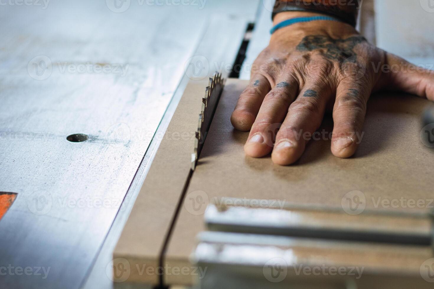 Crop male carpenter cutting wood with circular saw photo