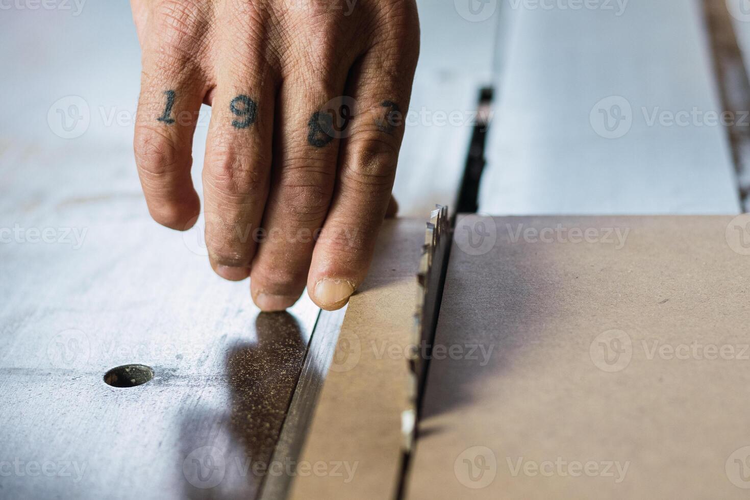 Crop male carpenter cutting wood with circular saw photo