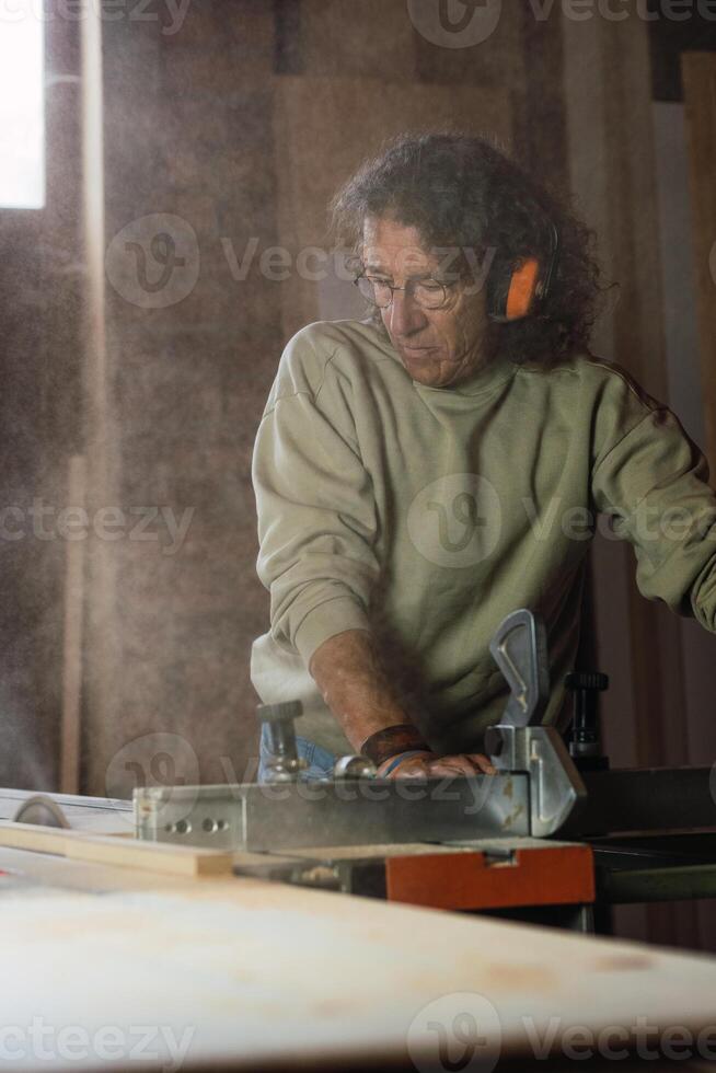 Carpenter cutting wood with circular saw in joinery photo