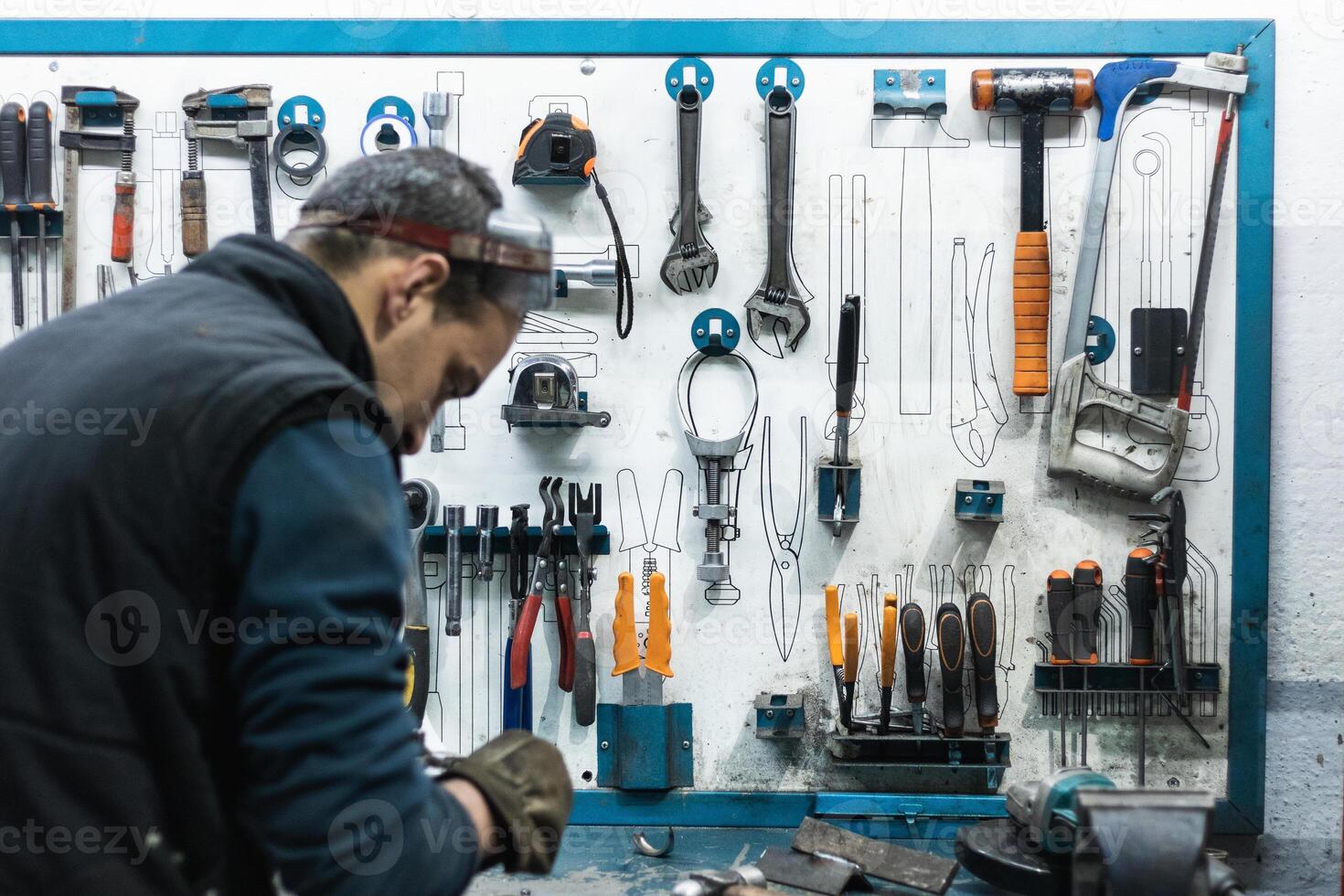 Professional mechanic using spanner while assembling vehicle engine details at workbench photo