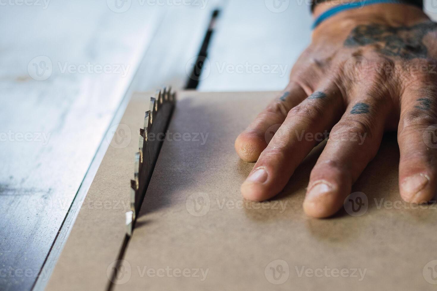 Crop male carpenter cutting wood with circular saw photo