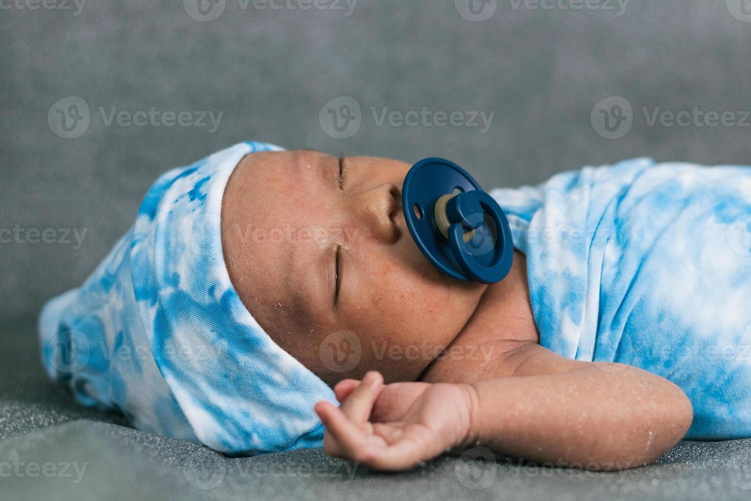 Newborn baby wrapped on soft blanket with pacifier photo