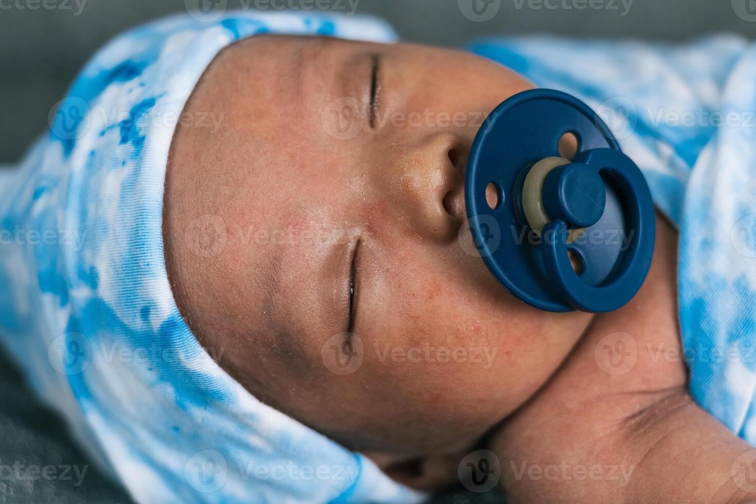 Newborn baby wrapped on soft blanket with pacifier photo