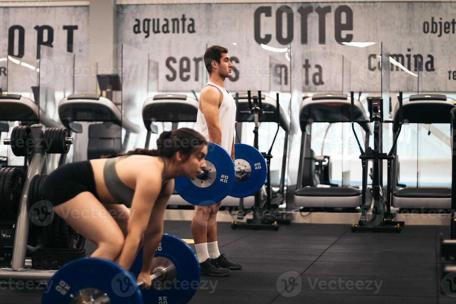 A man and woman in a gym doing squats photo
