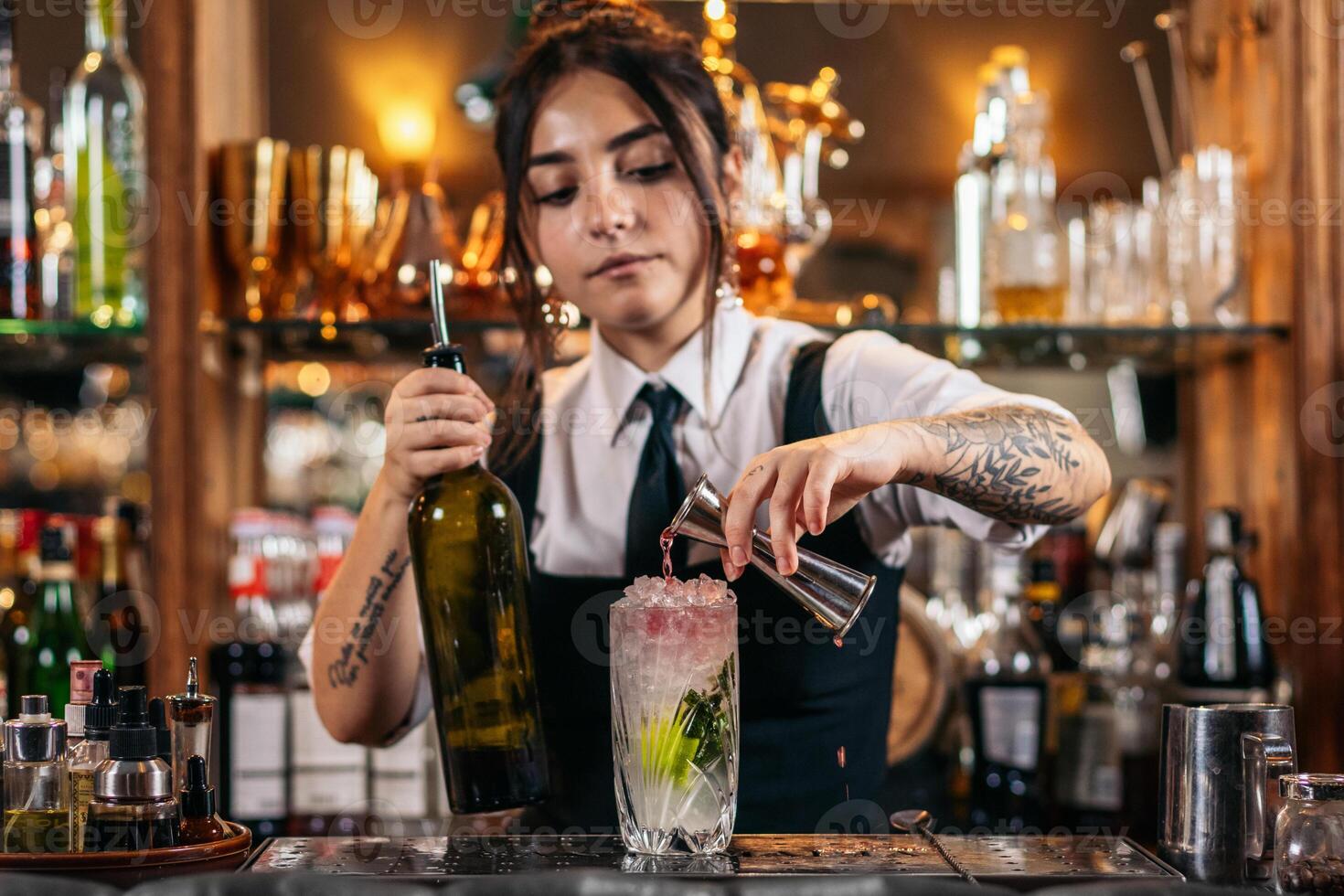 Female bartender preparing a cocktail in a traditional cocktail bar photo