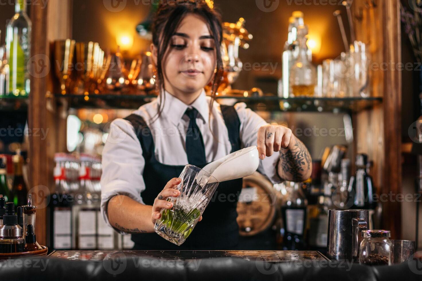 Female bartender preparing a cocktail in a traditional cocktail bar photo