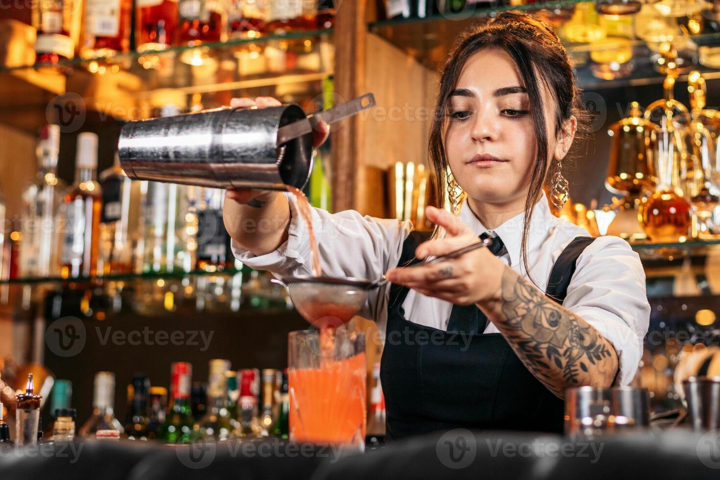Female bartender preparing a cocktail in a traditional cocktail bar photo