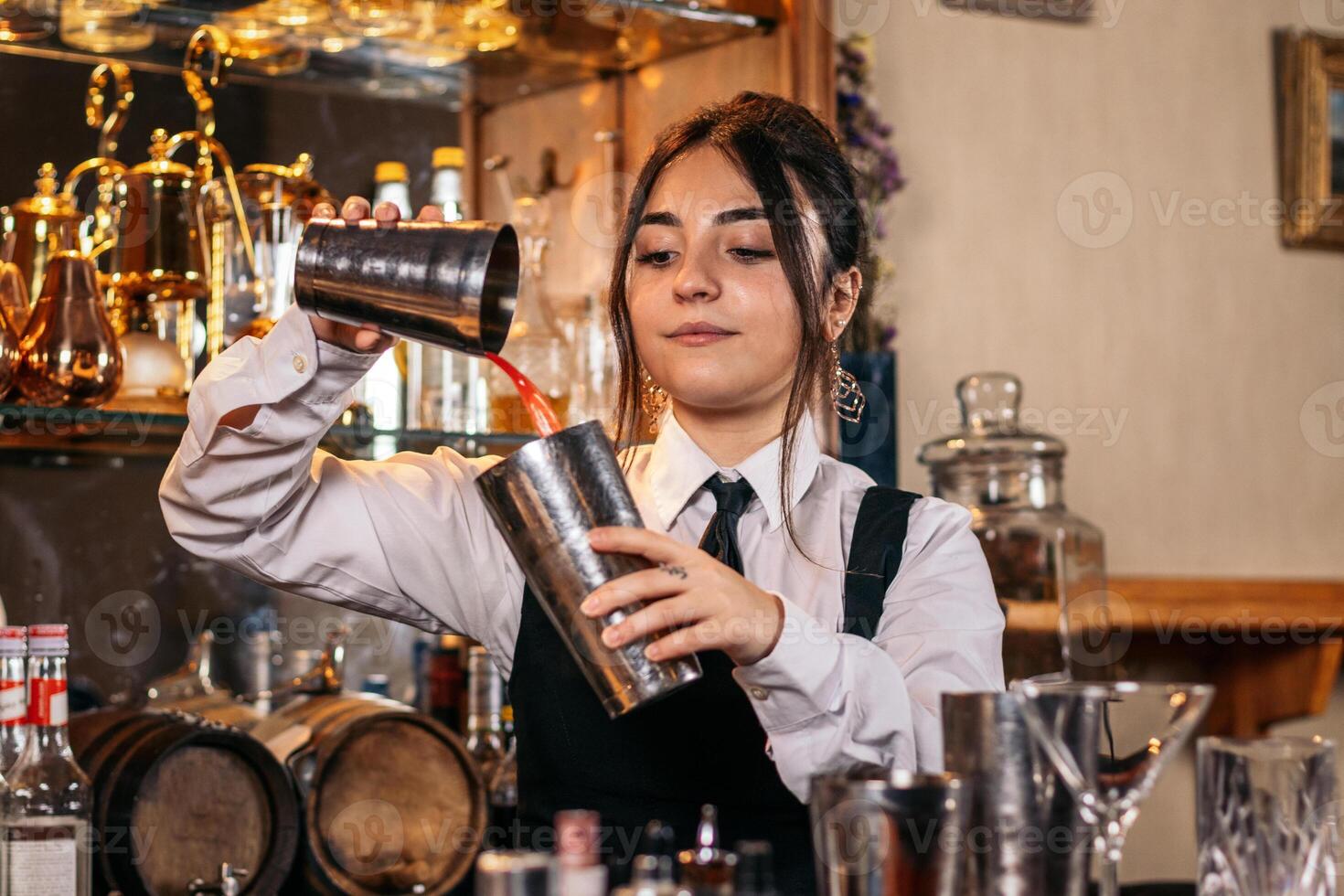 Female bartender preparing a cocktail in a traditional cocktail bar photo