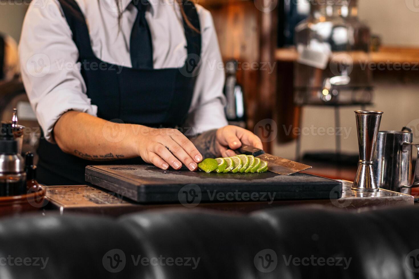 Close-up of a female bartender cutting limes to prepare cocktails photo