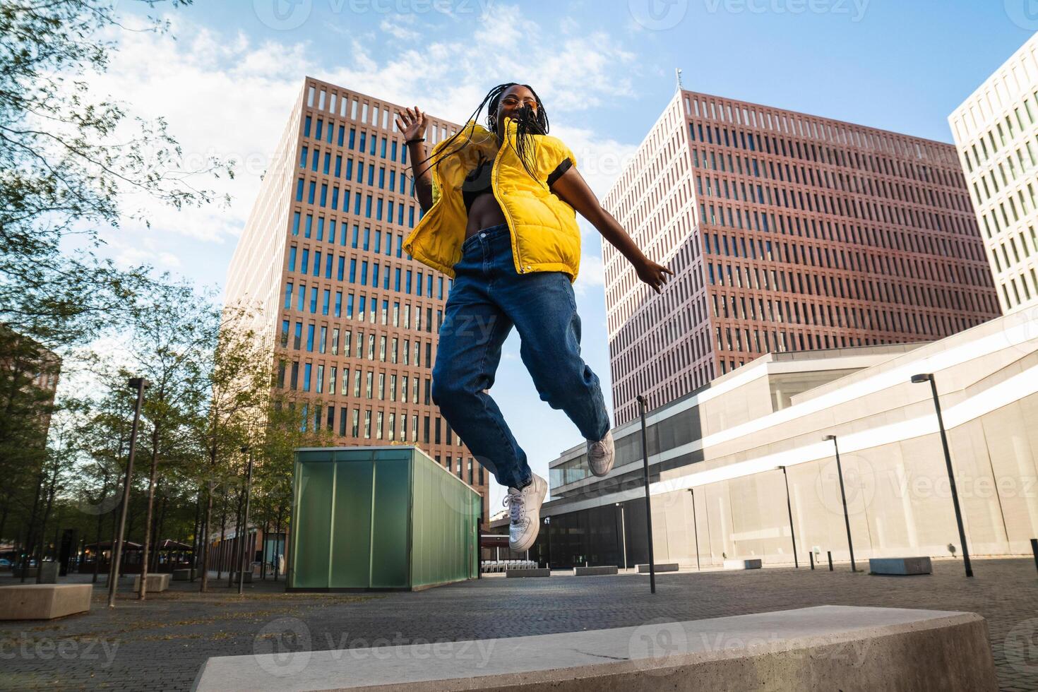 Excited ethnic female jumping on city street photo