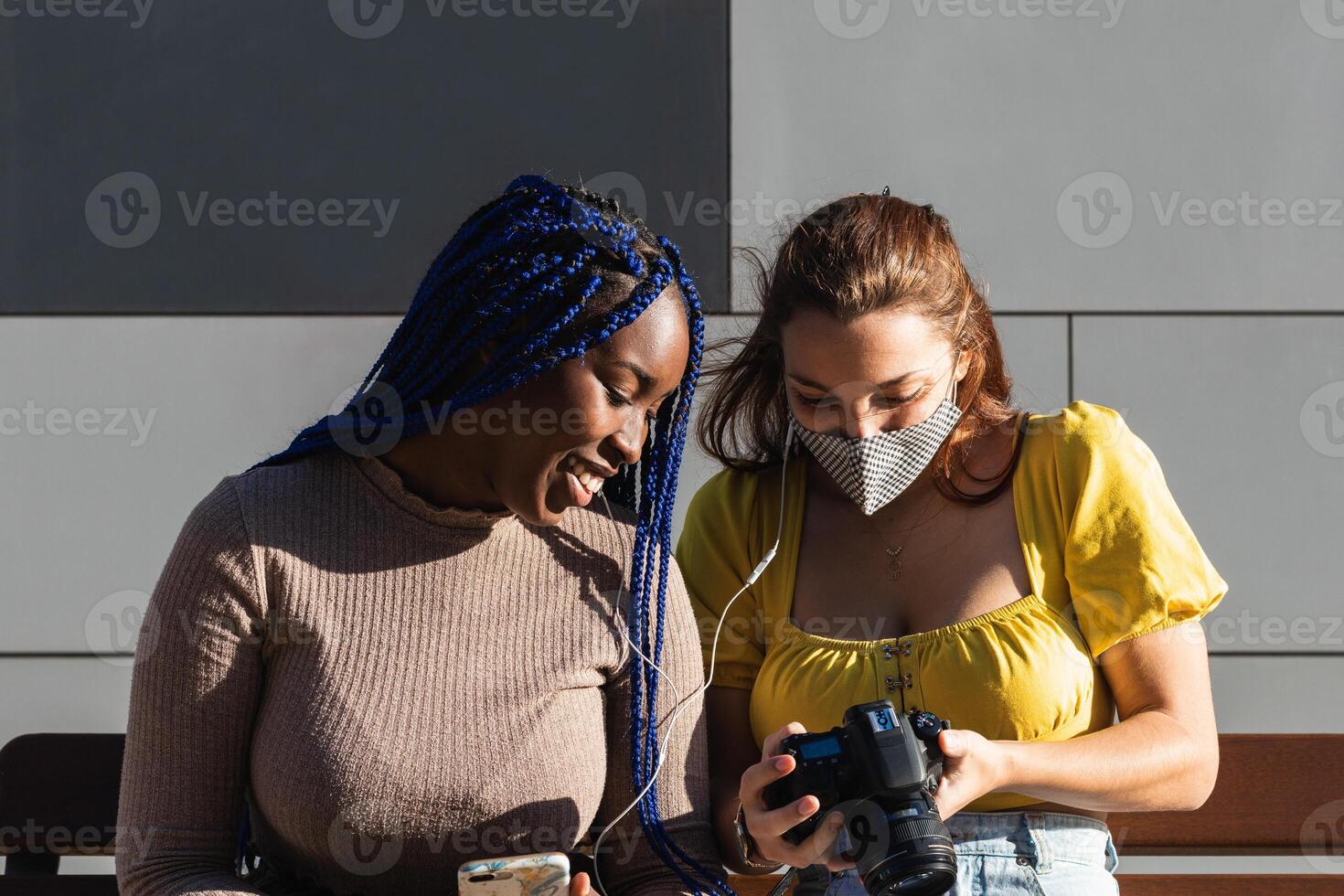 Cheerful multiethnic women looking through photos together