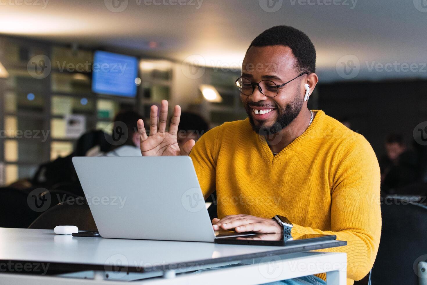Smiling black man calling on laptop in workspace photo