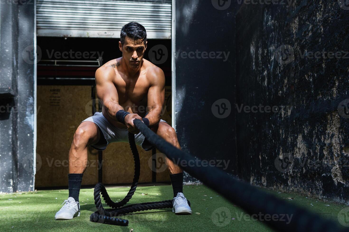 Muscular Hispanic sportsman pulling weight sled photo