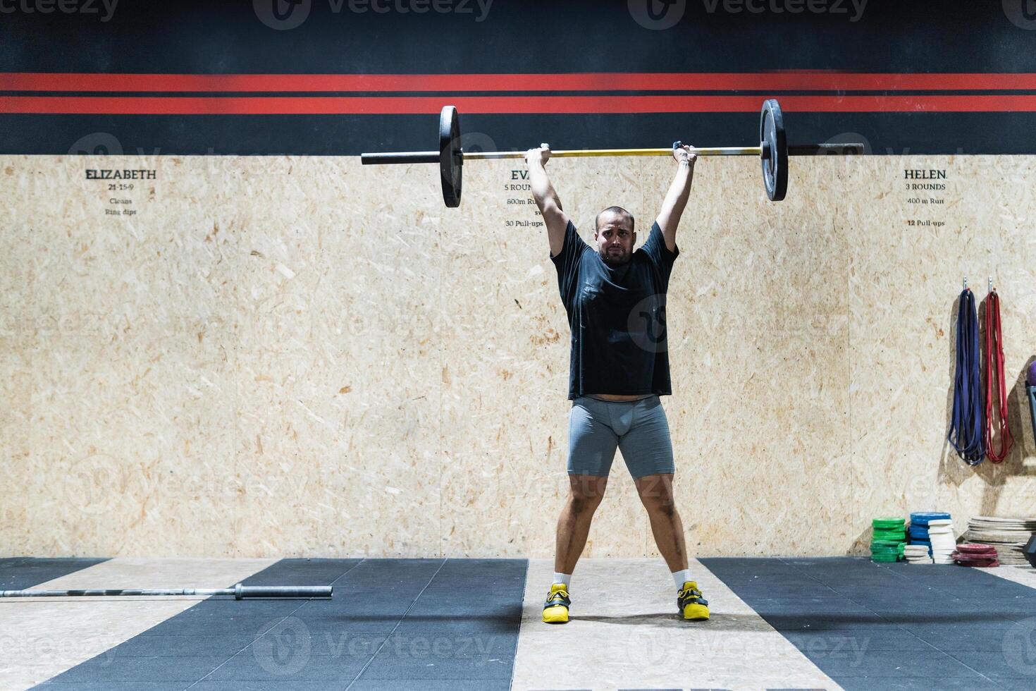 Muscular sportsman lifting heavy barbell photo