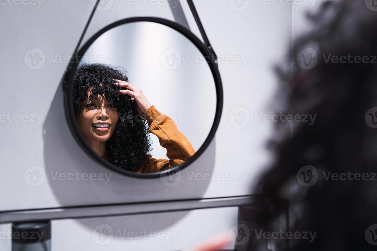 Smiling black woman looking at mirror at home photo