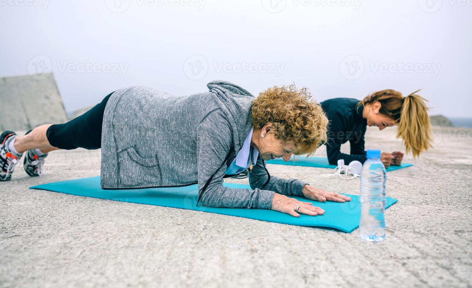 Senior woman and coach doing plank exercise photo