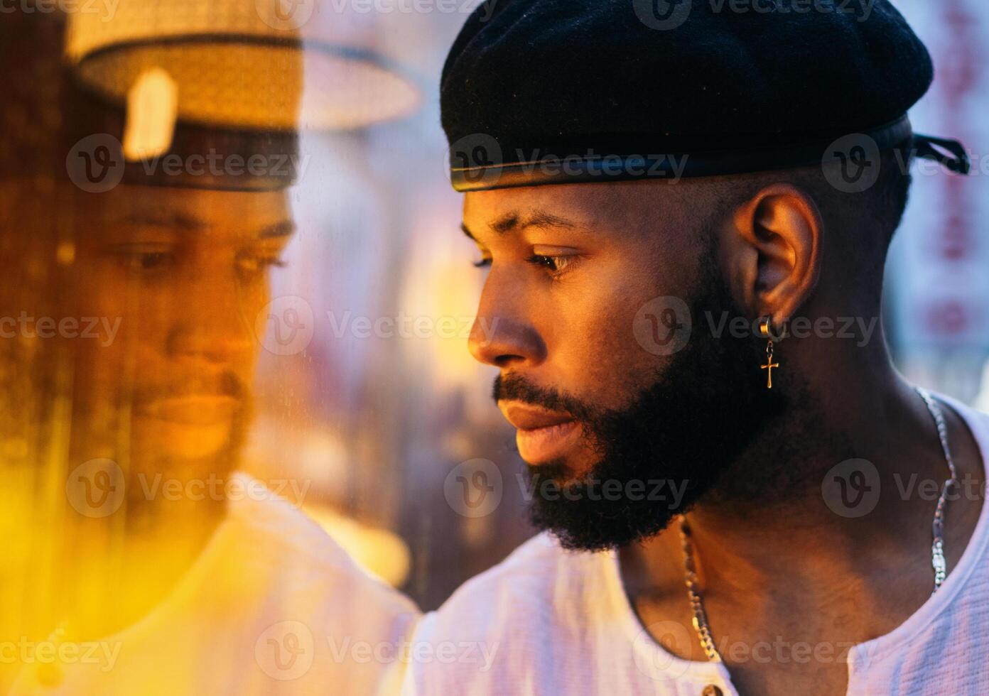 Black man near a glass. reflection and warm light photo
