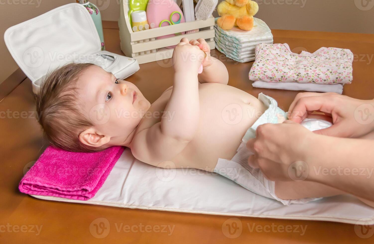 Mother changing diaper of adorable baby photo