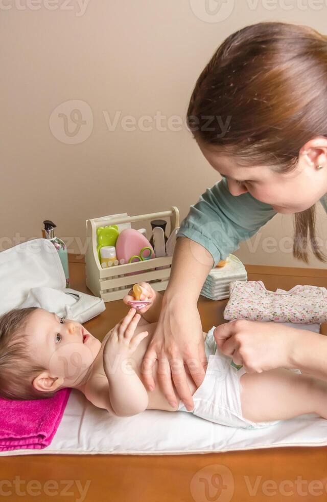Mother changing diaper of adorable baby photo