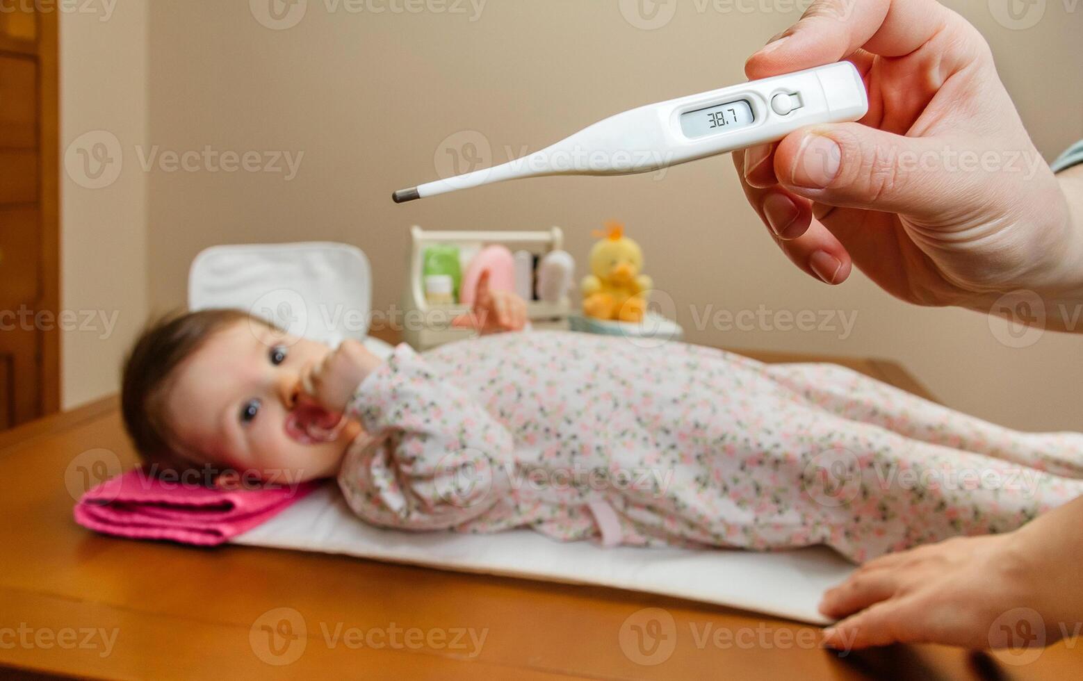 Mother hand measuring the temperature of baby in thermometer photo