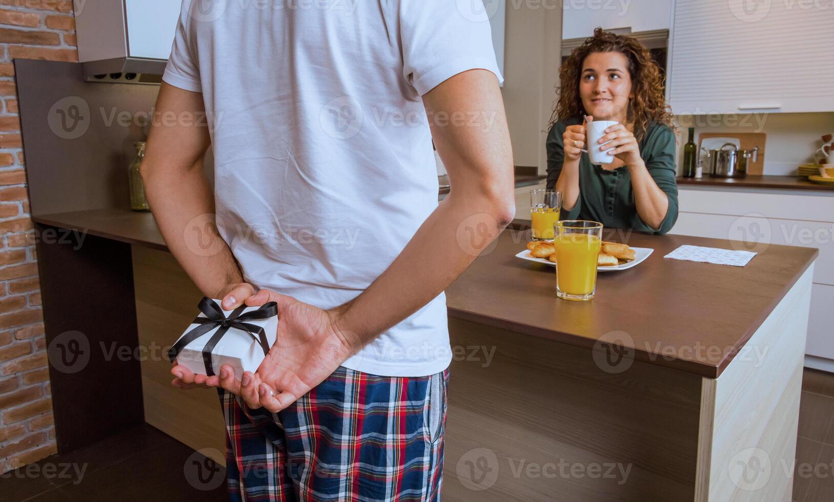 Man hiding a gift behind the back for his surprised girlfriend photo