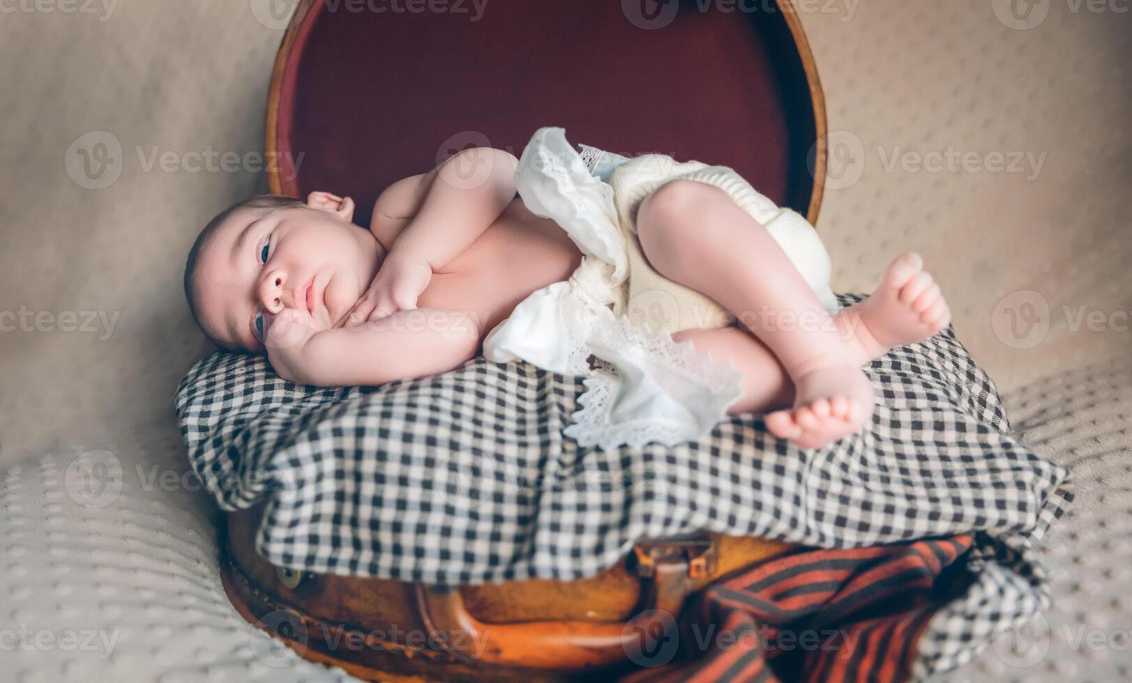 Newborn baby resting lying above of travel suitcase photo
