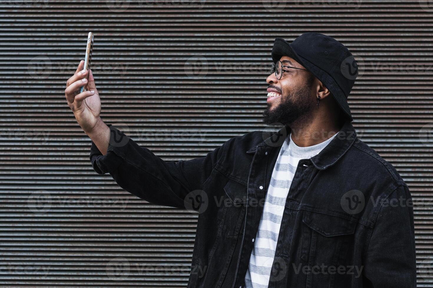 Laughing black man taking selfie on smartphone photo