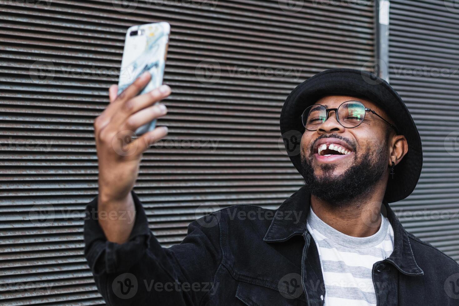 Laughing black man taking selfie on smartphone photo