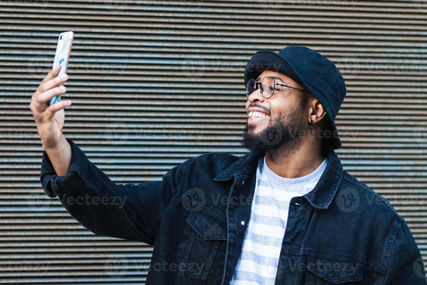 Laughing black man taking selfie on smartphone photo