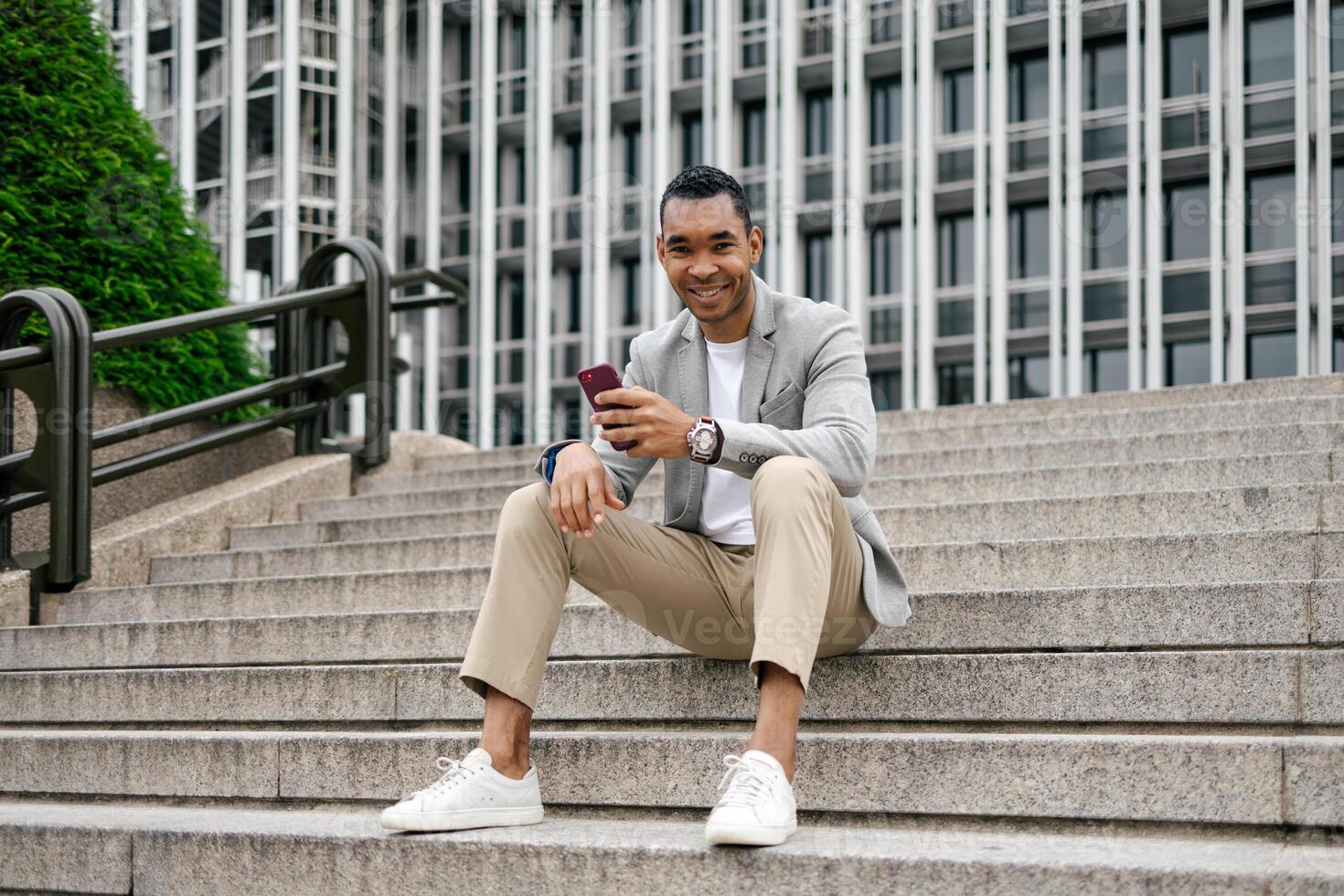 A man in a suit sitting on steps with his phone photo