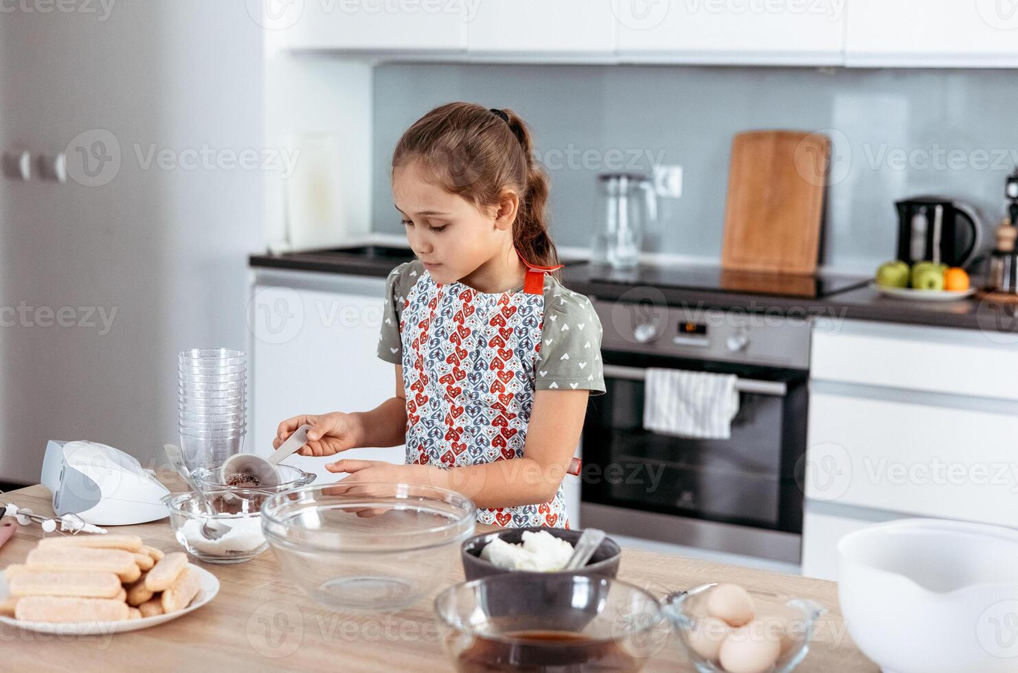 A little girl in an apron making cookies photo