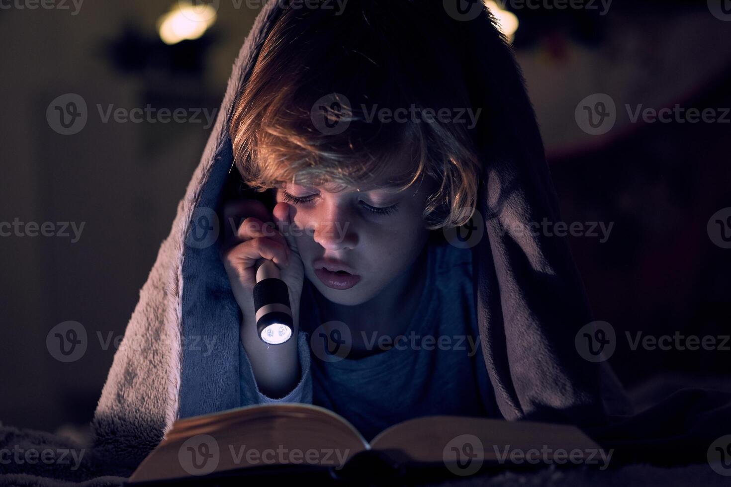 A child reading a book at night with a flashlight photo