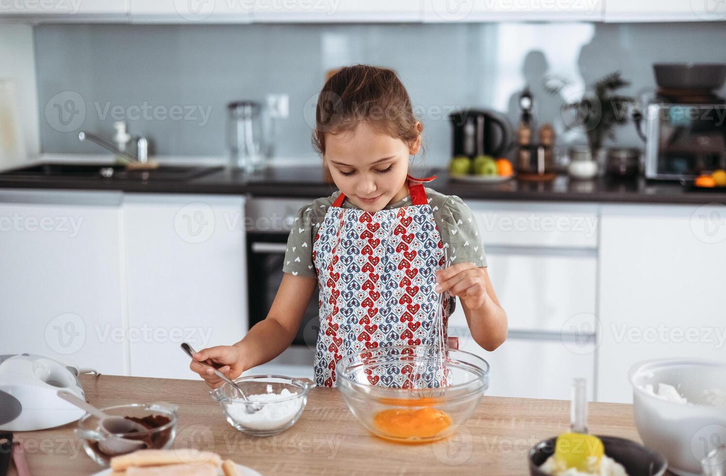 A little girl in an apron making a cake photo
