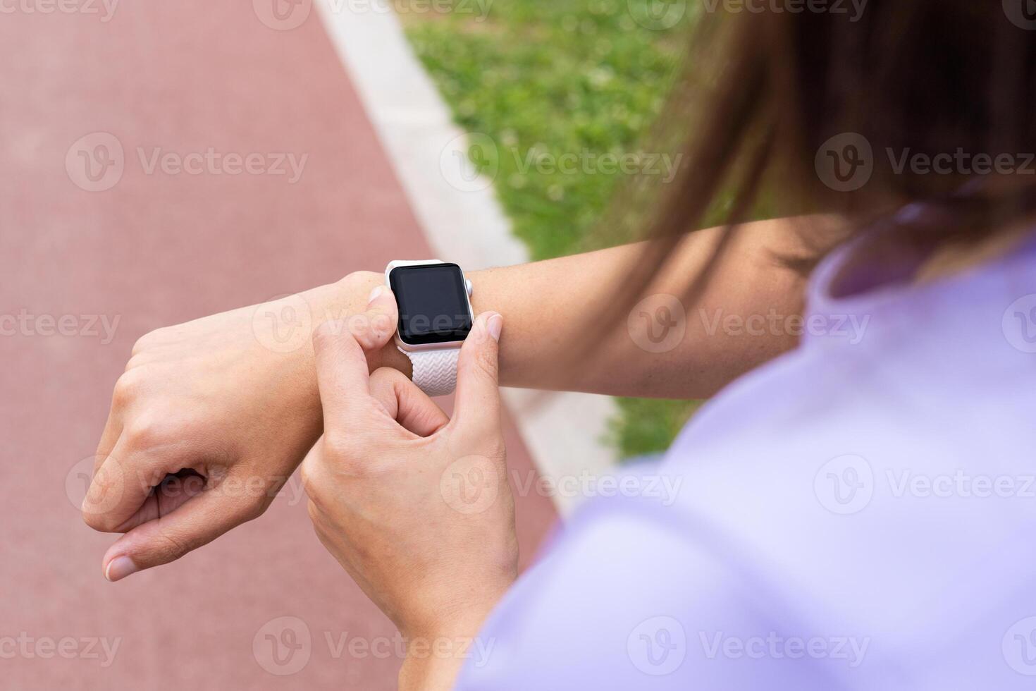 A woman is checking her watch on a running track photo