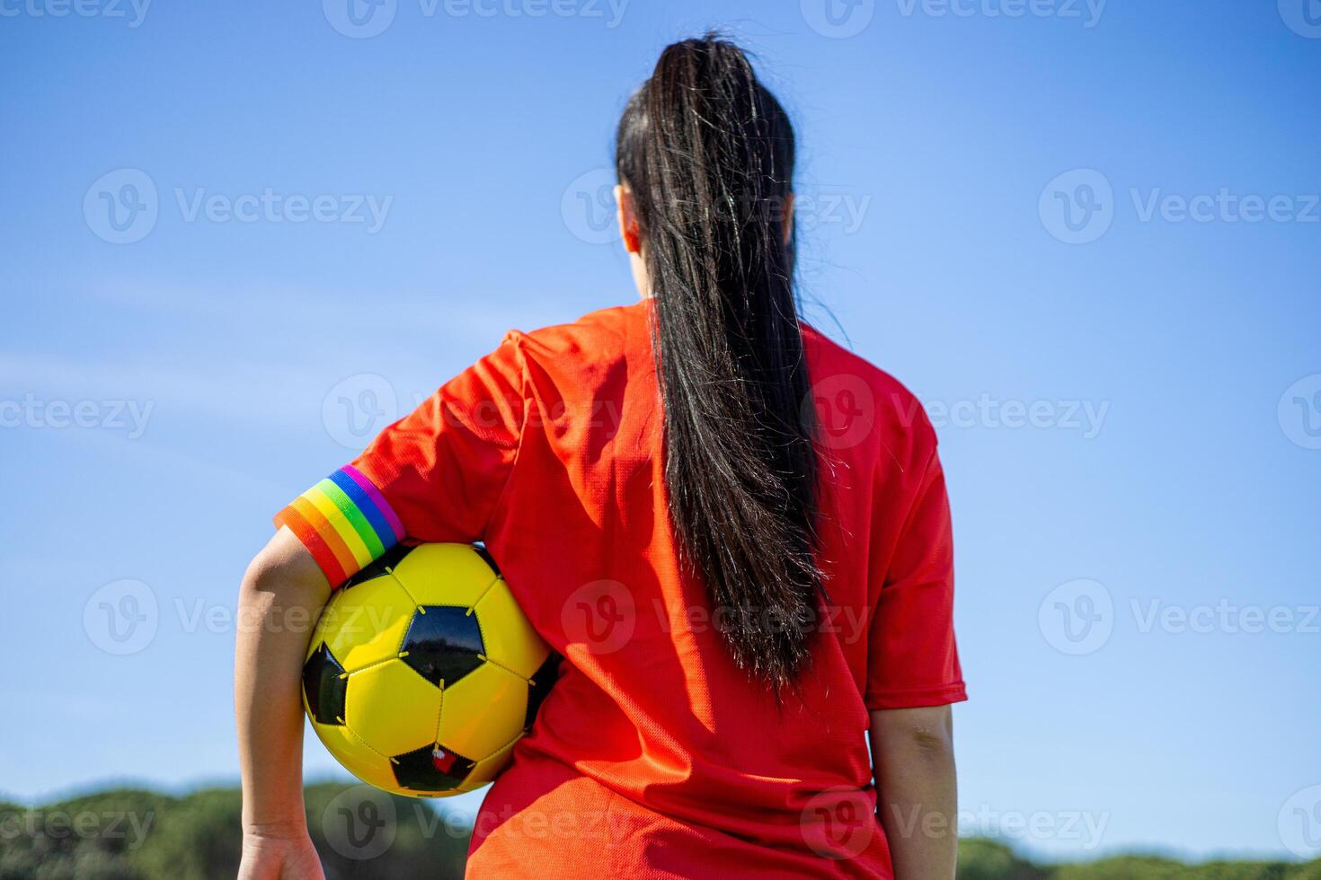 A woman in a red shirt holding a yellow ball photo