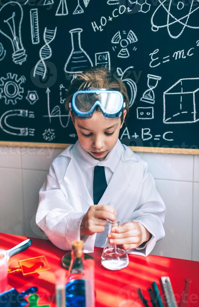 A young boy in a lab coat and goggles is working on a project photo