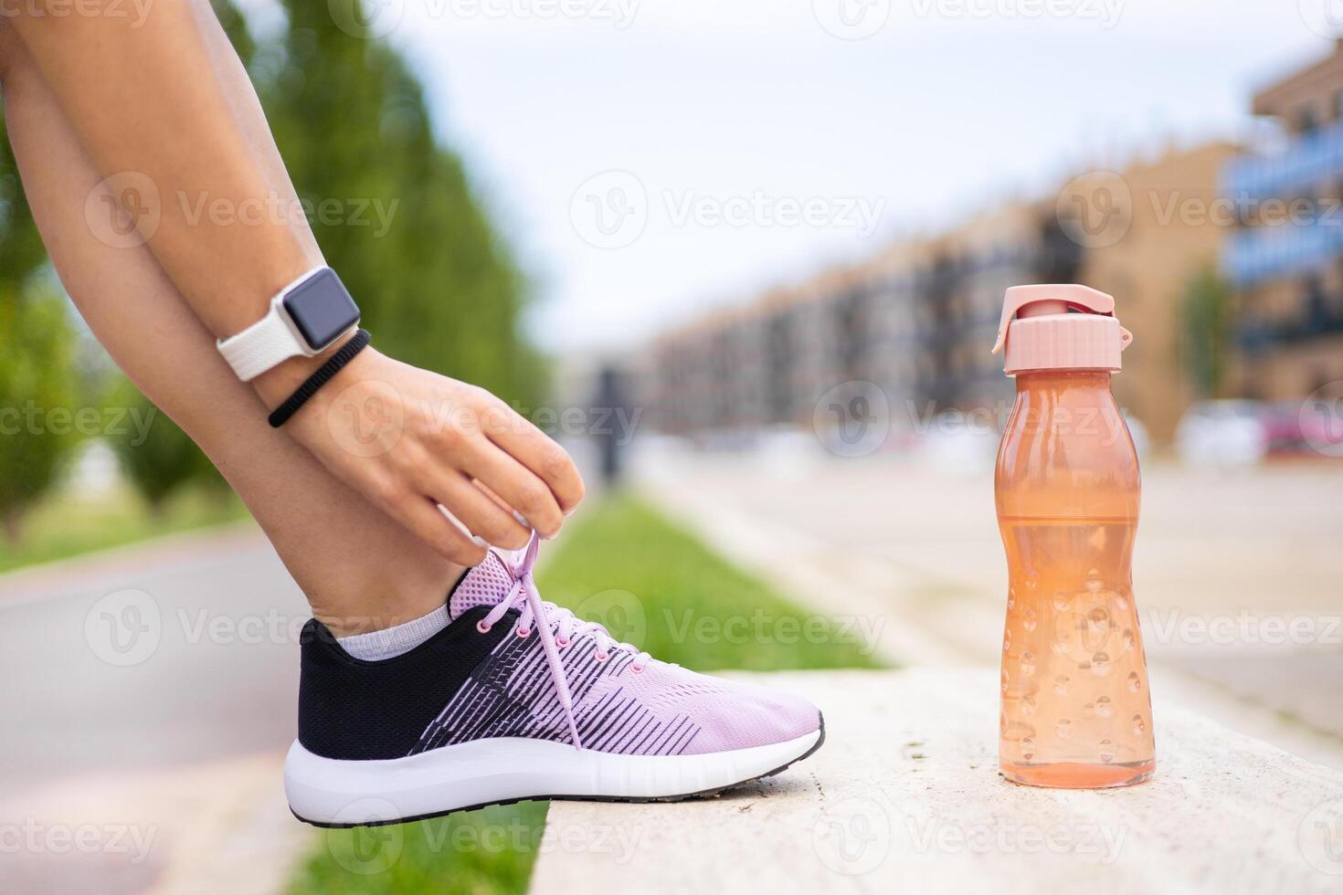 A woman is tying her shoe with a water bottle photo