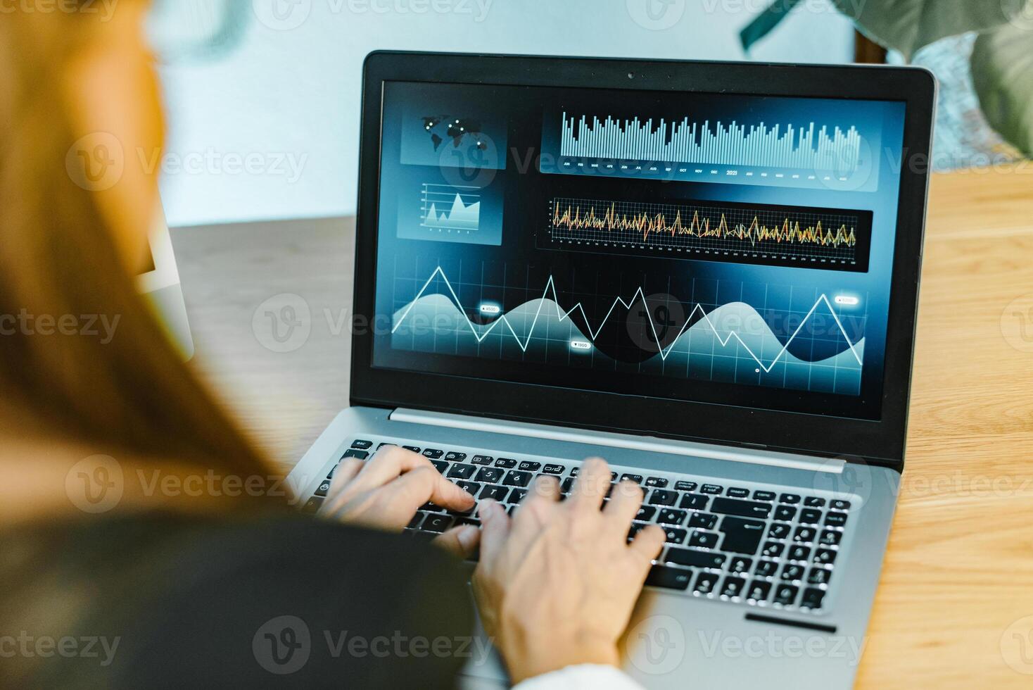 A woman is typing on a laptop with graphs on it photo
