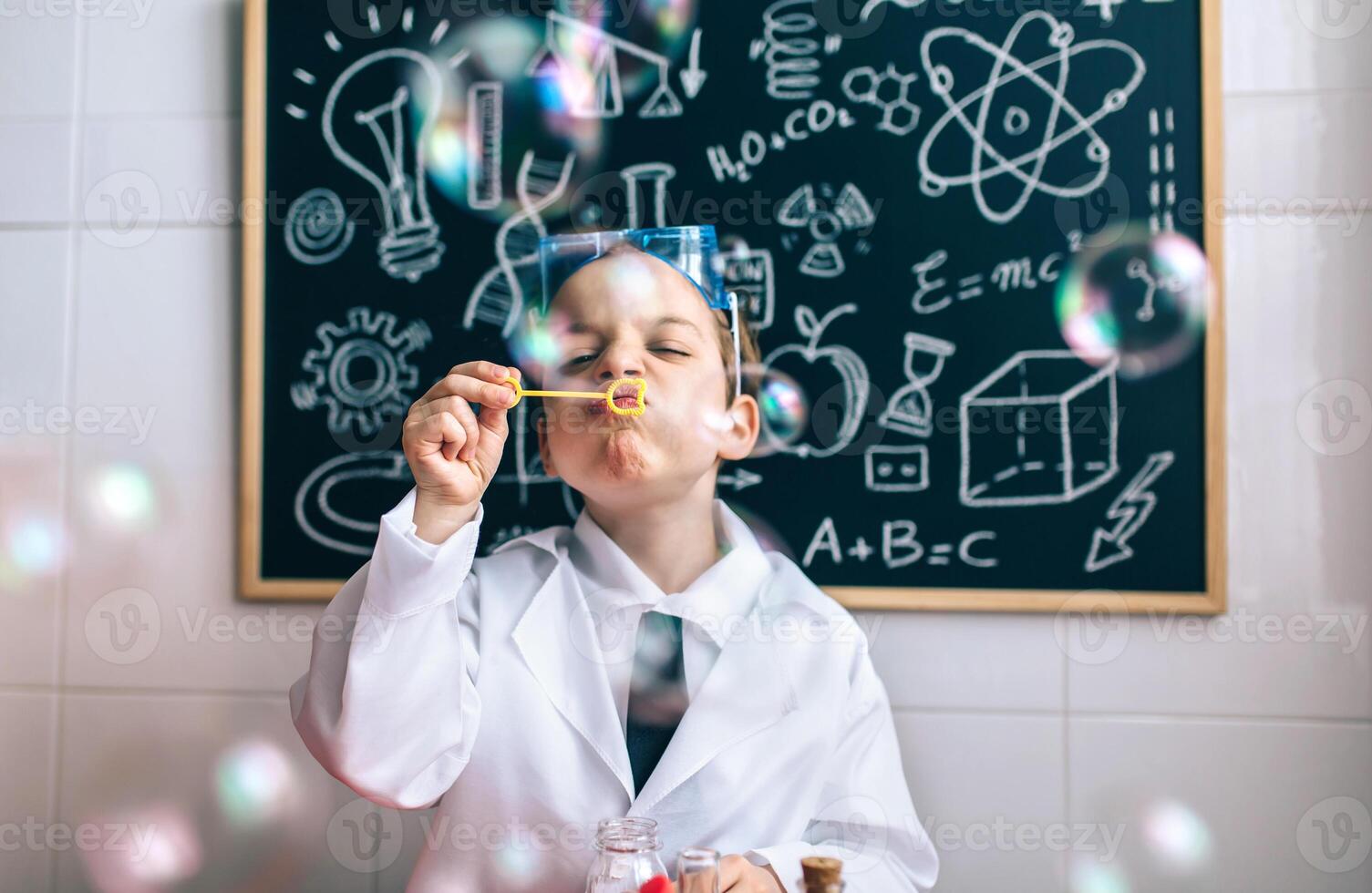A young boy in a lab coat blowing bubbles photo