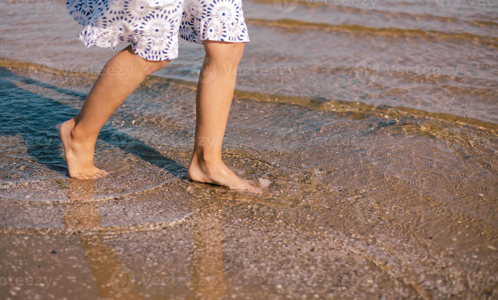 A woman walking on the beach with her feet in the water photo