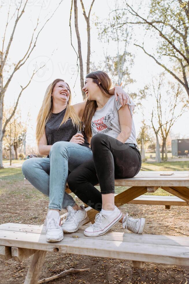 Two young women sitting on a picnic table photo