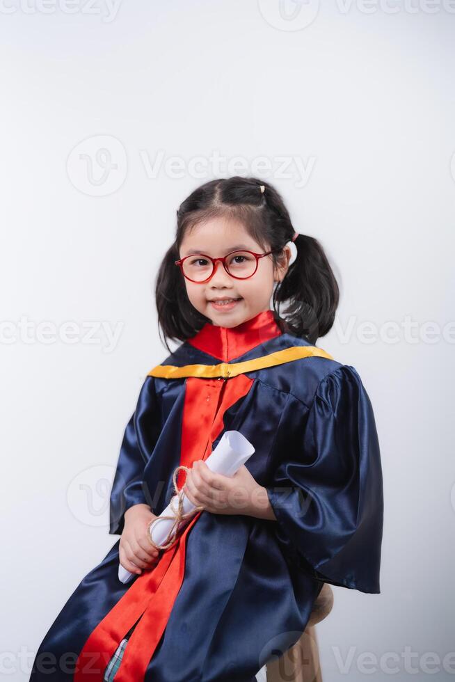 Happy Asian Asian Young Girl in Graduation Gown Holding Diploma and Smiling at Camera Against Plain Background photo