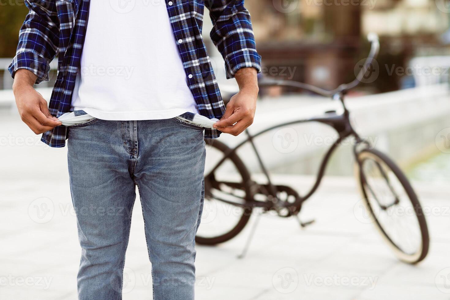 I Have No Money. Closeup of unrecognizable black man in blue casual style shirt showing his empty pockets in the street photo