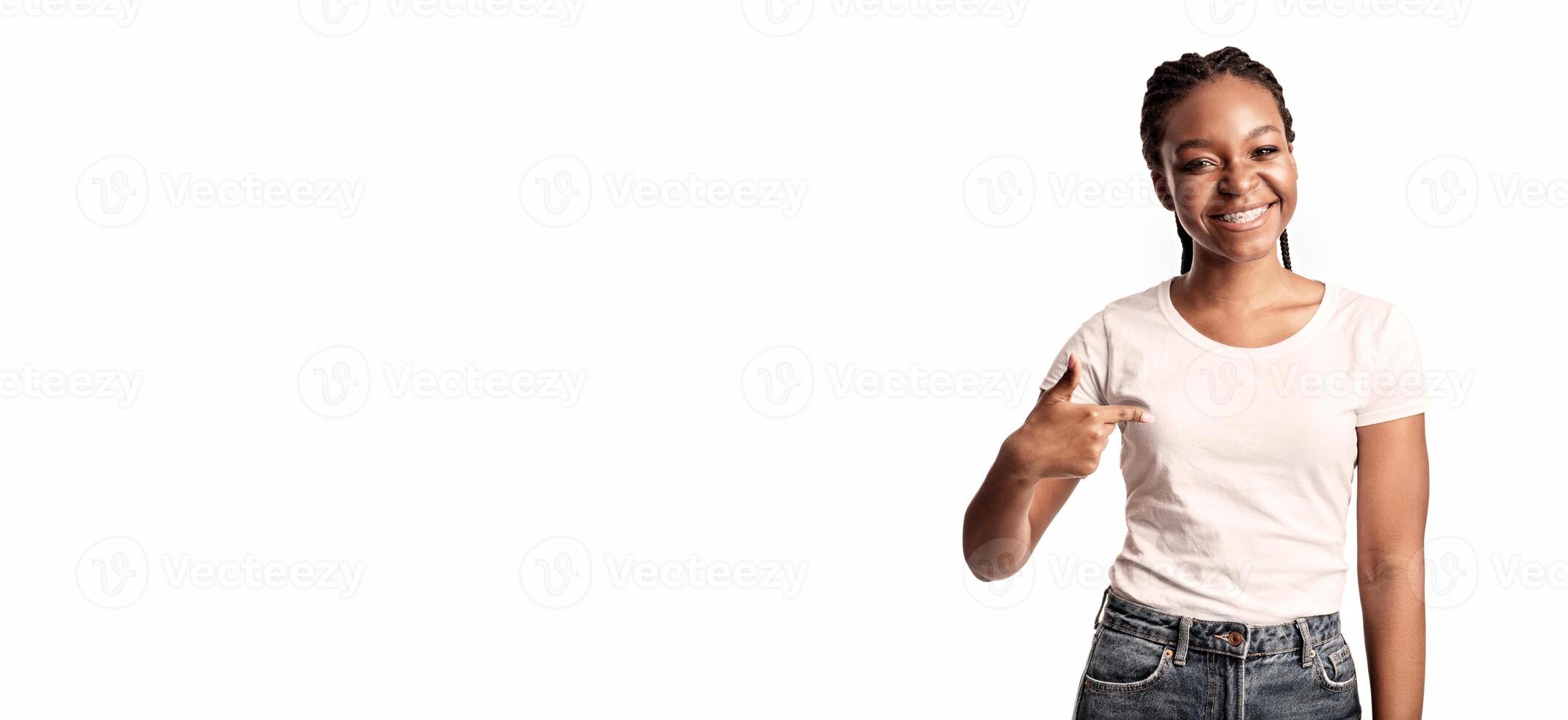 A cheerful young lady gestures with a smile, showcasing a sense of happiness. She is dressed in a white t-shirt and denim jeans, conveying a lively and friendly atmosphere. photo