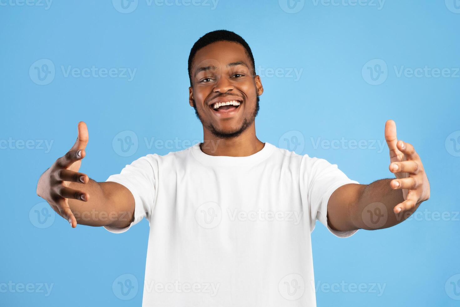 Give Me A Hug. Friendly Black Millennial Guy Stretching Both Hands Looking At Camera Posing Over Blue Studio Background. photo